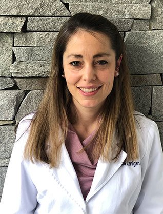 Jackie Lanigan, DDS, dentist at Telegraph Dentists, standing in front of stone wall